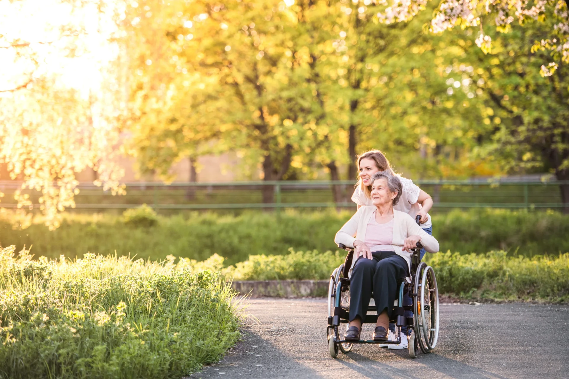 Caregiver warmly holding hands with an elderly woman in a sunlit living room